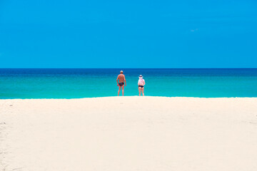 Two Female and Male  Tourists Standing on the white sand beach of Karon beach in Sumer, Phuket, Thailand