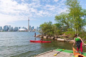 Setting out sea kayaking from a dock on Centre Island in Toronto, with the downtown city skyline in...