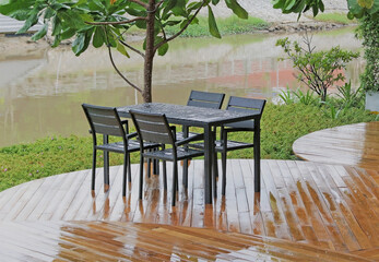 Garden tables and chairs in the rain on wooden decking overlooking a river view
