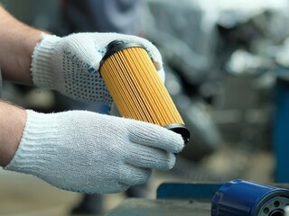 Spare parts. Car oil filter in the hands of an auto mechanic. Close-up, side view. Maintenance of a...