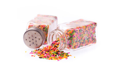 Color sprinkles sugar spilling out of a glass bottle isolated on white background