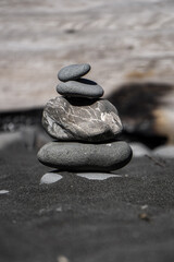 Fototapeta na wymiar Zen Stack of Stones on dark Sand