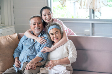 Asian young woman hug and take care senior parent grandmom and grandfather with smile in living...