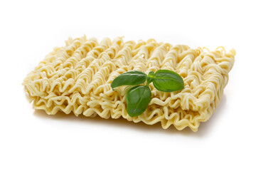 Dried Asian instant noodles decorated with a basil leaf on a white background.