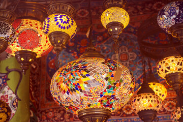 Middle Eastern lambas of different colors and sizes are hanging in the bazaar. Bright traditional Arabic and Turkish lanterns made of metal and glass, inlaid with mosaic details of different colors.