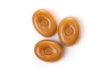 Three caramel candies on a white background close-up.