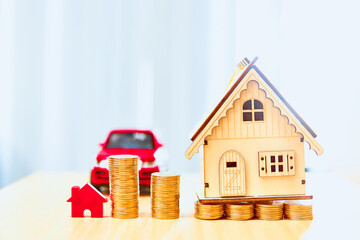 House models and red car models and gold coins placed on wooden boards.Credit or loan and earning for home and car in the family.Use money to exchange or buy in business and real estate.         
