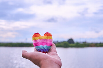Hands are holding a rainbow heart in the evening to replace the love in the Valentine.                     
