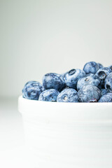 close up of bowl of ripe blueberries on white background