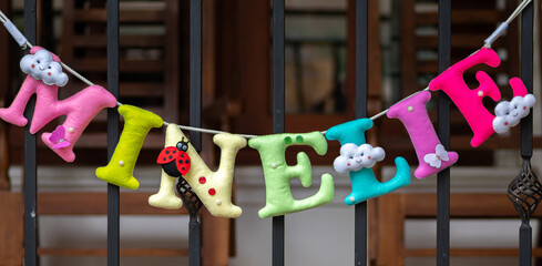 Fototapeta na wymiar 3d Plush letters name banner for a birthday party, decoration hanging in a white wall.