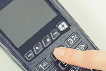 Obraz premium Payment terminal and finger entering PIN code. Credit card reader using for cashless paying