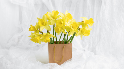 shopping bag. gift purchase concept. beautiful bouquet of fresh yellow daffodils in a craft package on a white background
