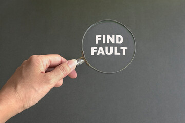 Magnifying glass with text Find Fault. Dark grey background.