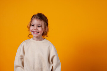 Cute little girl laughing on a yellow background. Space for text.