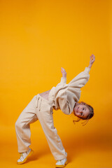 Cute little girl dancing on a yellow background. Space for text.