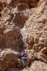 Male rock climber looks ahead to the next quickdraw on a red rock wall in the desert of Diablo Canyon outside Santa Fe, New Mexico, USA
