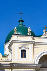 Fototapeta na wymiar Green dome with a cross and a roof with sculptures against the blue sky