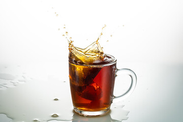 splash from falling piece of sugar in a transparent mug on a white background