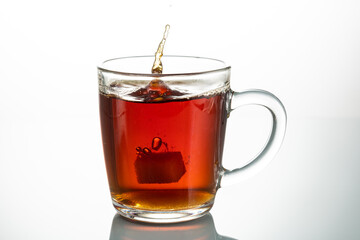 splash from falling piece of sugar in a transparent mug on a white background