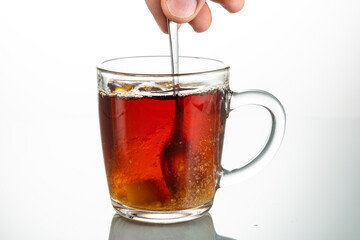 stir with a spoon a piece of sugar in a transparent mug on a white background