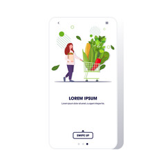 woman pushing trolley cart with different vegetables healthy lifestyle vegan fresh food concept full length smartphone screen mobile app copy space