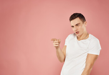 cheerful man gesturing with his hands in a white t-shirt on a pink background