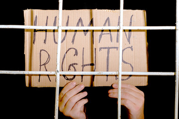 the concept of human rights freedom of speech hands hold a cardboard sign with the inscription human rights behind the iron prison bars