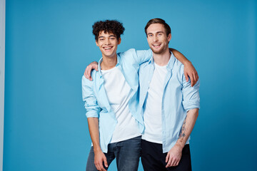 guy with curly hair in a shirt and a t-shirt on a blue background and a young man friends fun