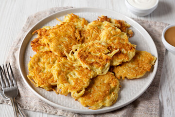 Homemade Potato Pancakes Latkes with Apple Sauce and Sour Cream on a white wooden surface, side view. Close-up.
