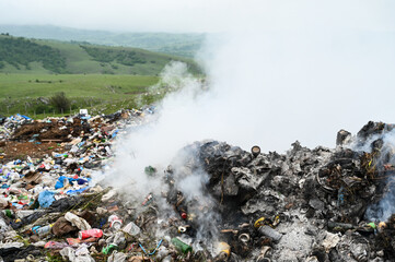 Open landfill site with burning waste. Burning pile of illegal garbage dump near city. The smoke...