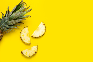 Ripe pineapple slices, pineapple with foliage on a yellow background. Top view, flat lay