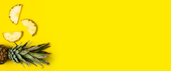 Ripe pineapple slices, pineapple with foliage on a yellow background. Top view, flat lay. Banner
