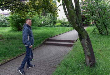 Obraz premium middle-aged man, 60 years old, walks along the footpath in the square and smiles