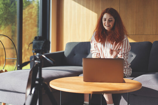 Front view of business woman recording video with digital camera, tripod and laptop