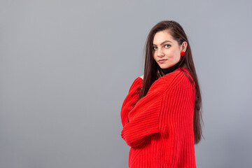 young emotional teenage female with glasses dressed in a red sweater posing on a gray background