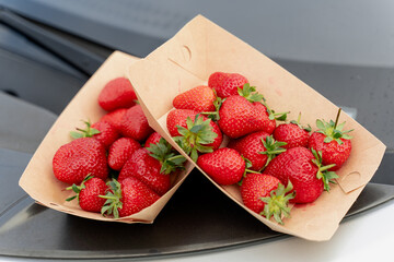 Strawberry in disposable eco plates on car background for delivery.
