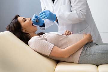 Dentist Treating Teeth Of Pregnant Woman Patient Lying