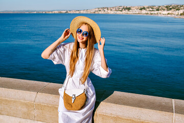 Pretty blonde woman wearing trendy straw hat and blue sunglasses