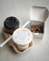 Hot and cold latte in a takeaway cups served with freshly baked brownies. High angle view.