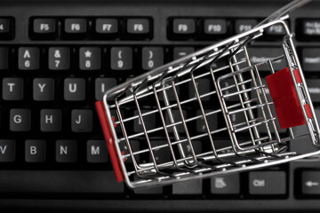 Small shopping cart on the keyboard. Close up, top view. Online shopping concept.