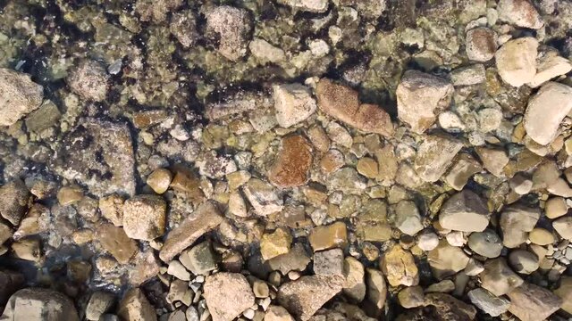 Sea waves on a stones shore , zoom out smooth top view 4k