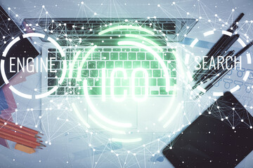 Blockchain theme hologram drawings over computer on the desktop background. Top view. Multi exposure. Concept of cryptoeconomy.