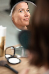 woman applying make up in front of a mirror