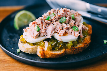 Open sandwich with canned tuna, egg and pickled cucumber dressing served with lime.