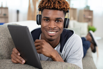 Obraz premium man on sofa with headphones and digital tablet