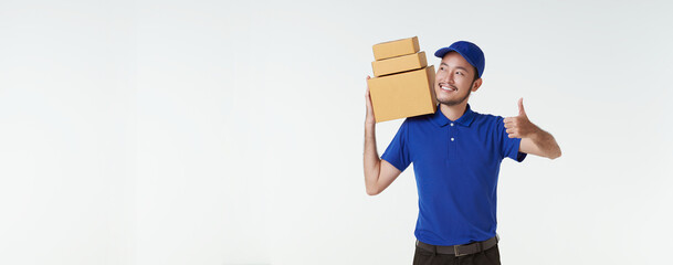 Asian delivery man wearing in blue uniform standing with carry parcel post box isolated over white...