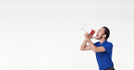 Happy young Asian man in blue shirt shouting announce into megaphone isolated on white background in studio. - obrazy, fototapety, plakaty