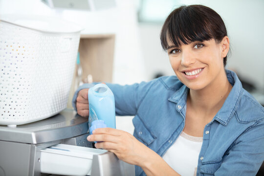 a happy housewife woman in laundry room with washing machine