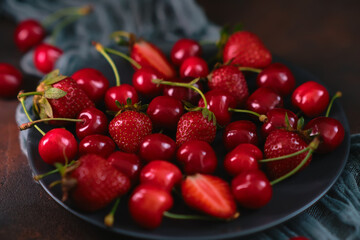 Fresh organic summer mix of strawberry and sweet cherry in round stone plate