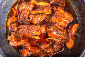Chinese red braised spare ribs. Braised pork, brisket and ribs in red hot sauce in a saucepan, close-up - Caribbean, Chinese, Asian style